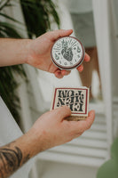 By Elementum Ignis Oil-Based Pomade, geschlossener Tiegel mit Ignis-Deckel neben der geöffneten Made-in-Poland-Verpackung