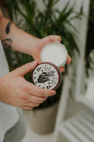 By Elementum Ignis Oil-Based Pomade, geöffneter Tiegel mit cremefarbener Pomade und Deckel mit Ignis-Logo
