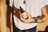 Pomp & Co. Beard Oil, Mann hält das grüne Glasfläschchen